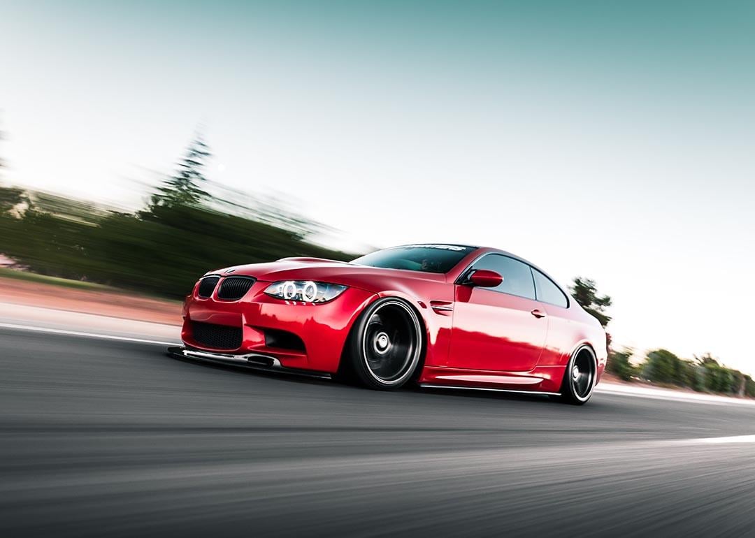 Red BMW driving on road with motion blur in background.