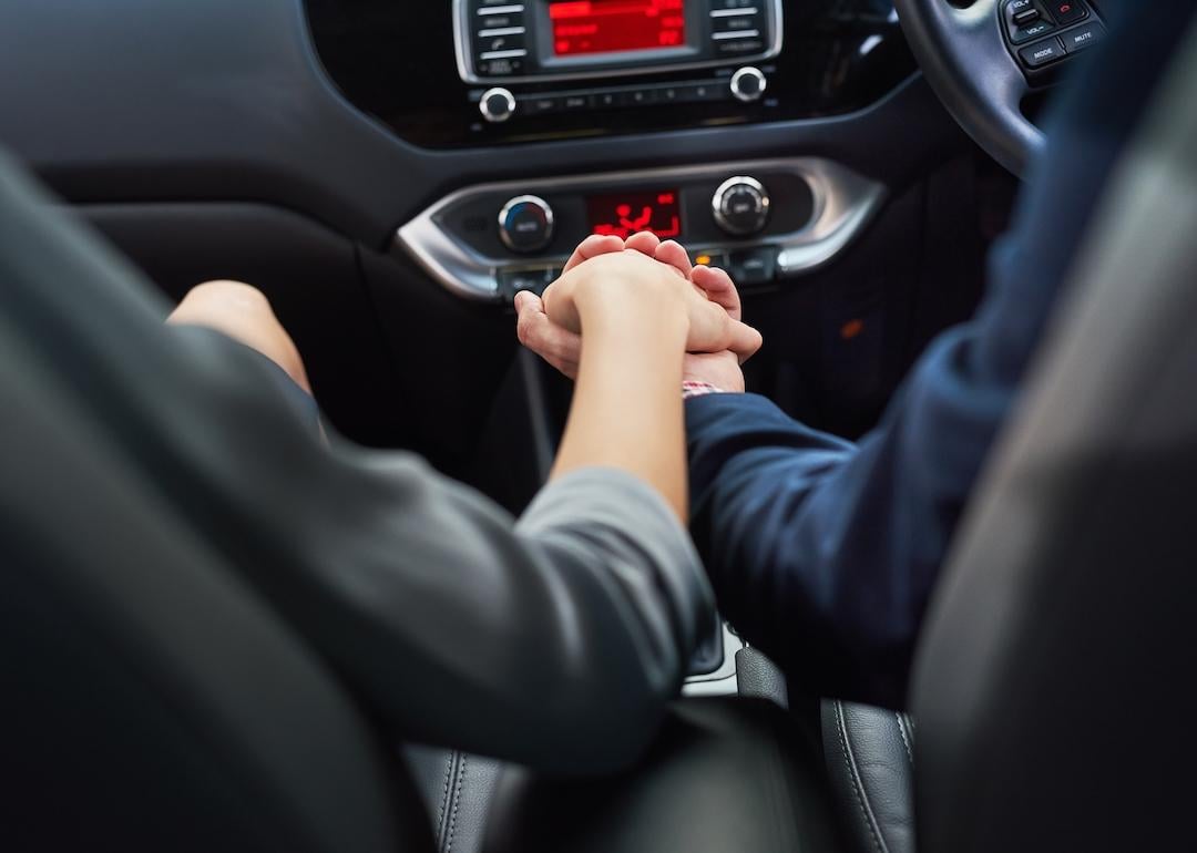 Couple holding hands in car while commuting to work.