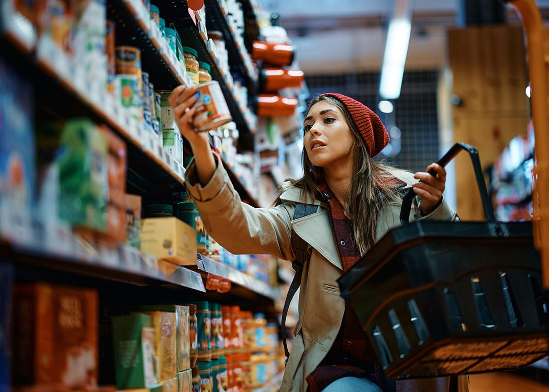 A young woman carefully selecting items to purchase in a grocery aisle.