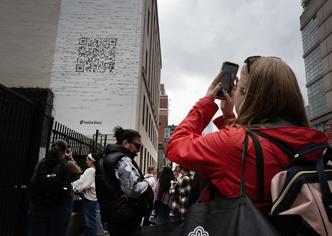 Taylor Swift fans gather outside a building where a mural featuring a large QR code was being painted to promote Swift's latest album, "The Tortured Poets Department," on April 17, 2024 in Chicago, Illinois.