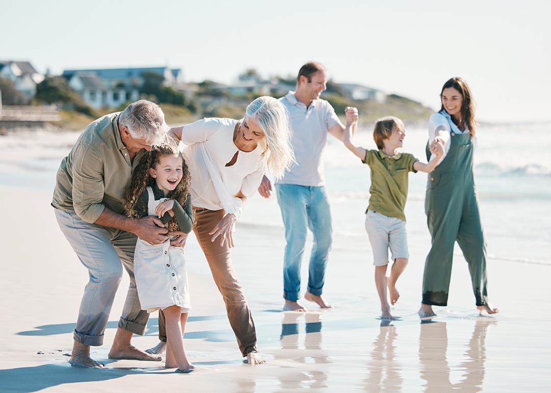 Big family with grandparents play and laught at the beach.