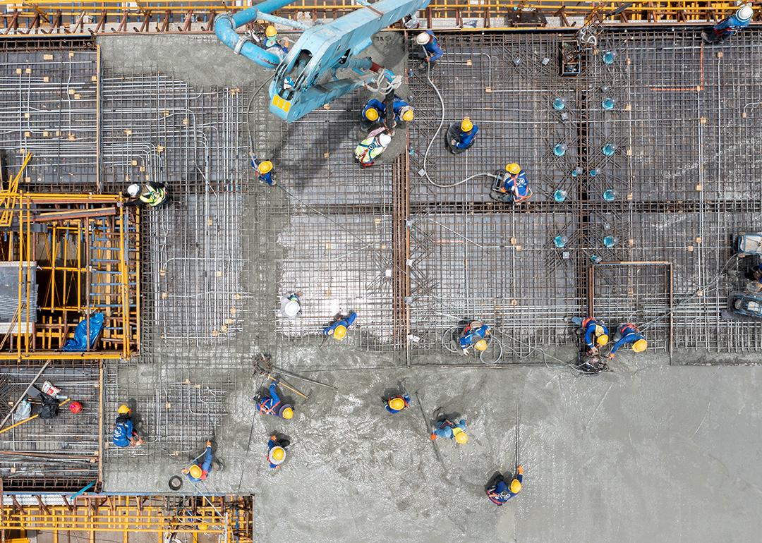 An aerial view of construction workers pouring concrete for a project site.