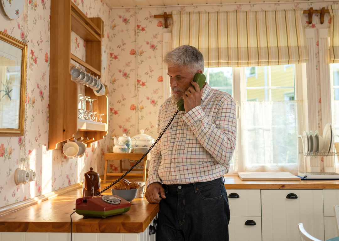 An older man speaking on landline phone.