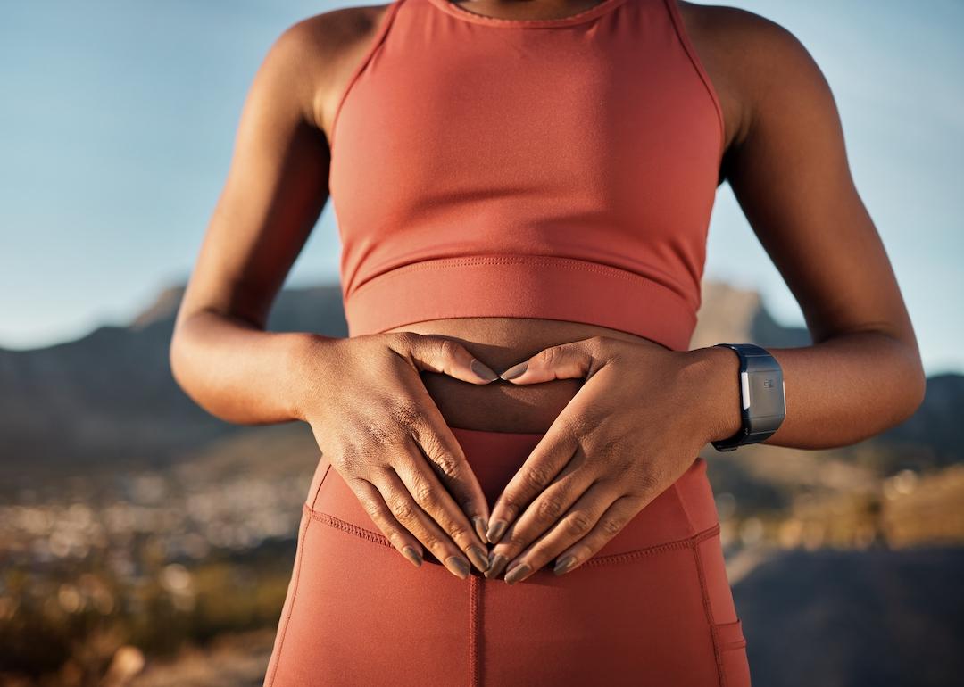 Person in athleisure wear putting hands on stomach.