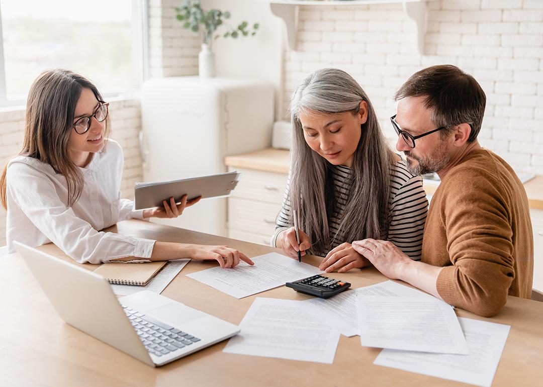 A couple consults with a finance professional while looking at a set of documents.