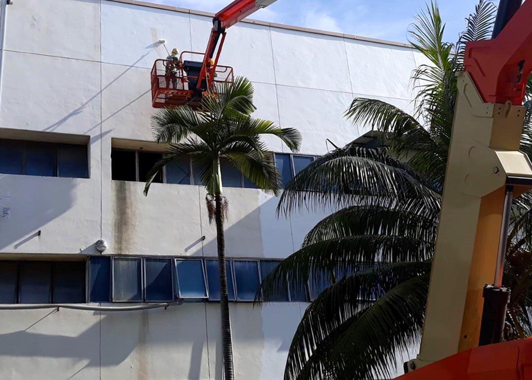 A worker in a boom lift sprays a coat of cool paint on the roof of a building at the test site in Singapore.