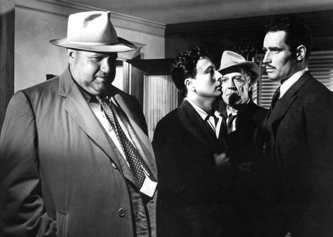 Orson Welles, Charlton Heston and other men gathered in room in a scene from the film 'Touch Of Evil', 1958. 