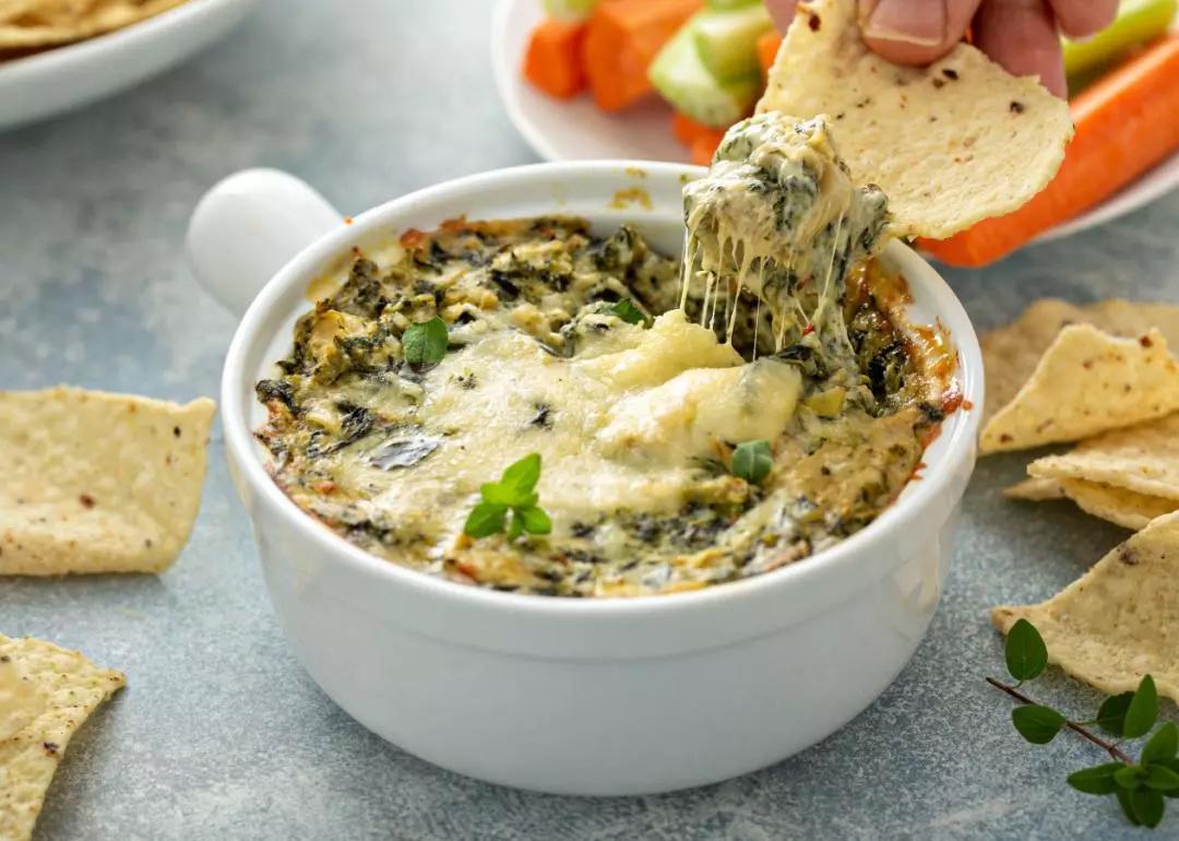 Artichoke spinach dip in a baking dish with a cheese pull.