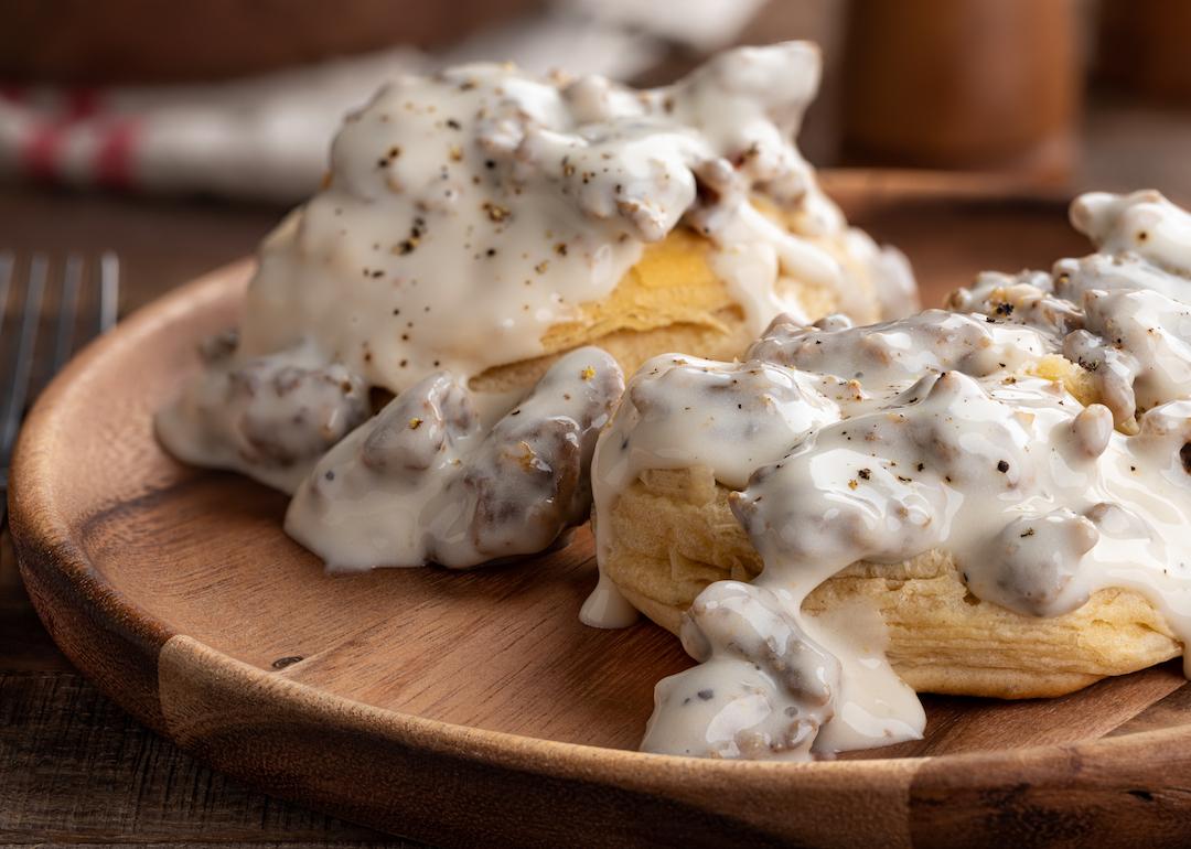 Closeup of biscuits and creamy sausage gravy on a wooden plate.