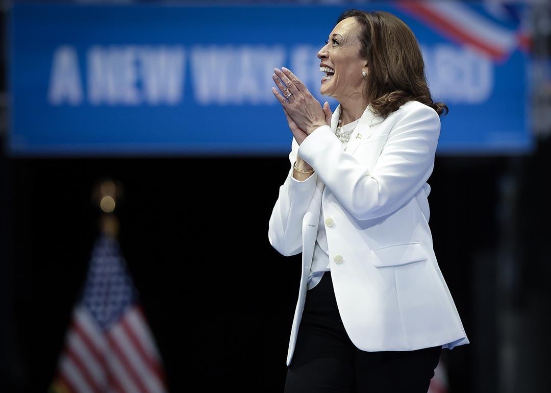 Democratic presidential nominee, U.S. Vice President Kamala Harris wearing white, greets the crowd as she arrives on stage at a campaign rally at the Enmarket Arena August 29, 2024 in Savannah, Georgia.