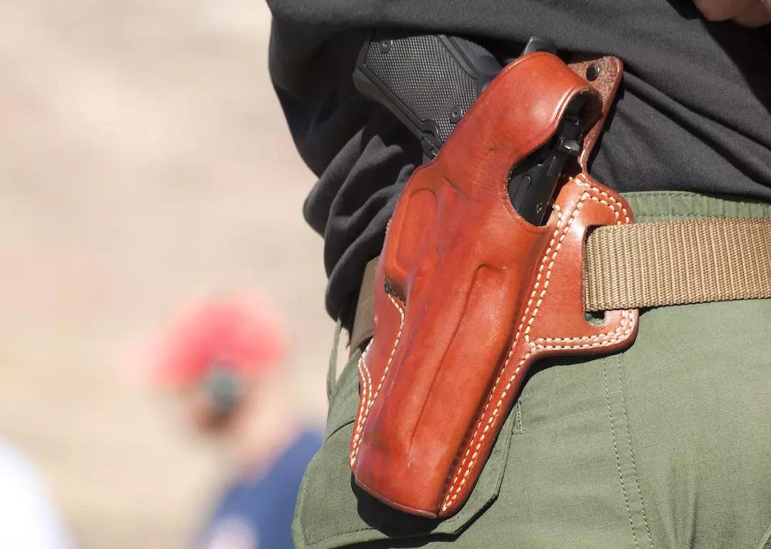 Gun in brown leather holster on belt.