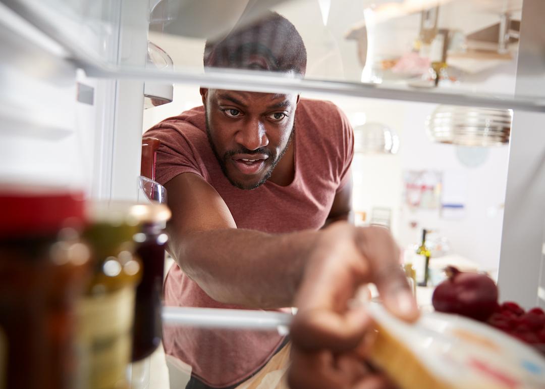 View from inside refrigerator as person reaches for groceries.