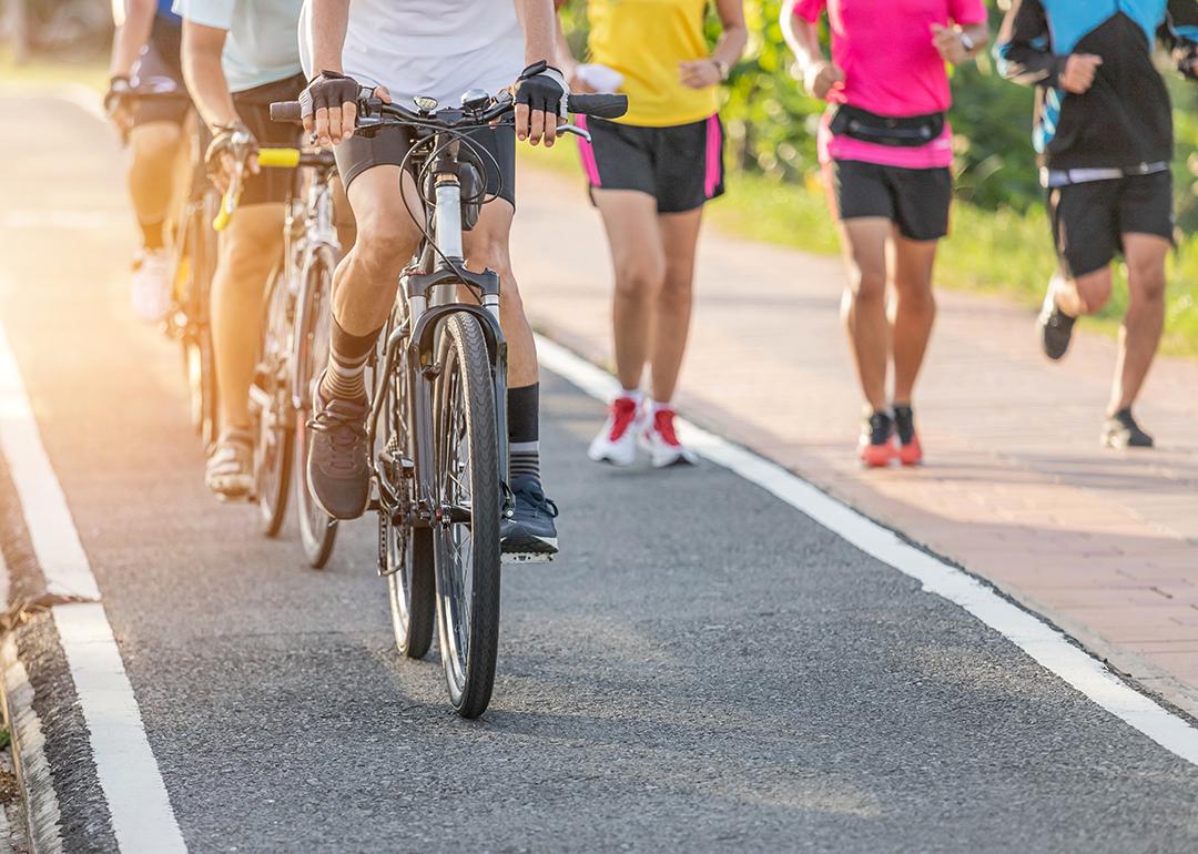 A group of cyclists and runners in their own lanes in the morning.