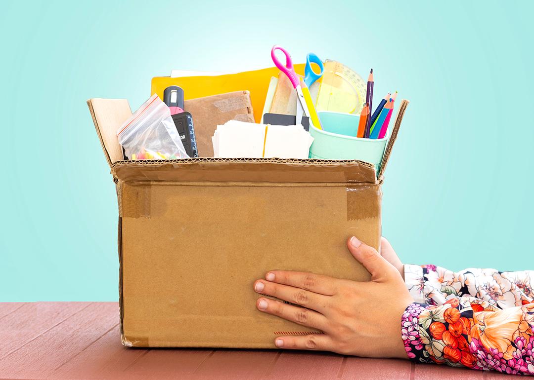 A teacher's hands holding a box of school supplies.