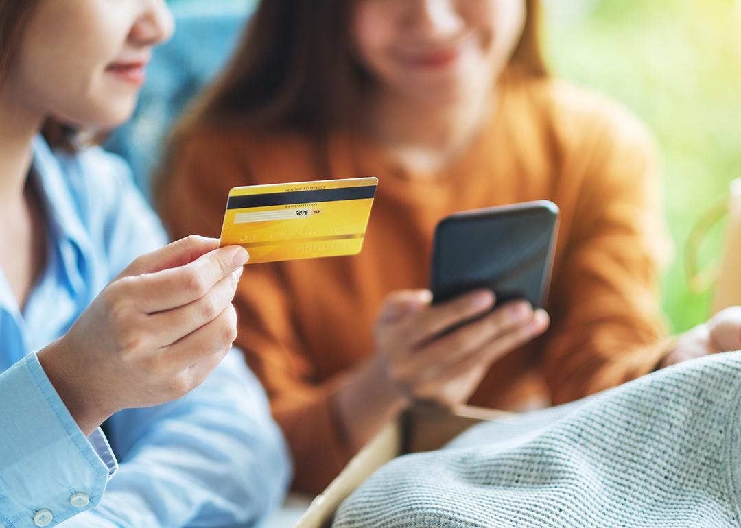 Two women happily looking at a phone and credit card.