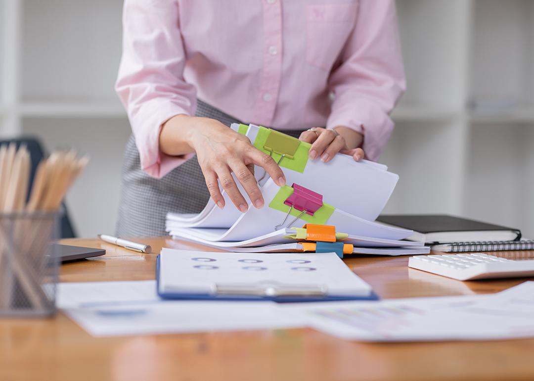 A professional stacking piles of business documents and reports.