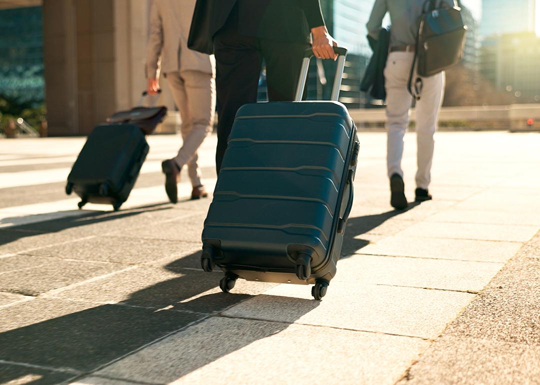 A group of three business professionals walking with their luggages for a travel.