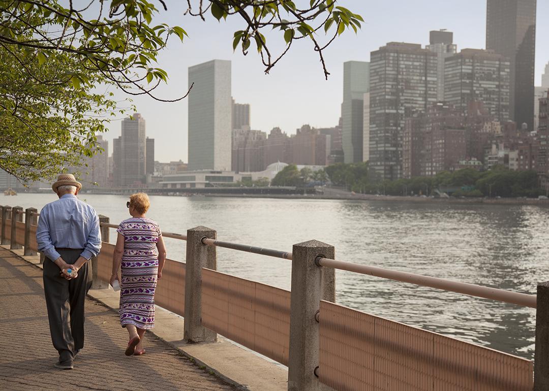 A senior couple walking along a park path in New York City.