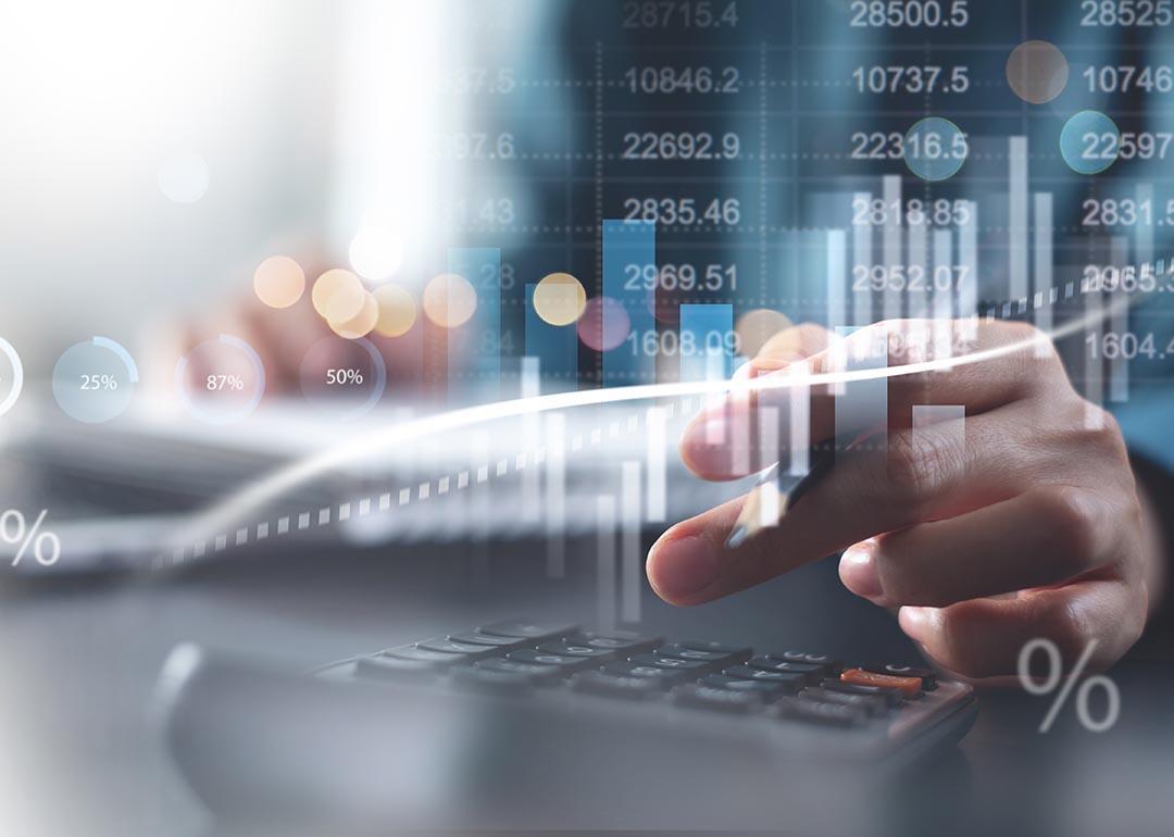 Calculating taxes concept, close up of person doing finances and on calculator with graphs superimposed in foreground.