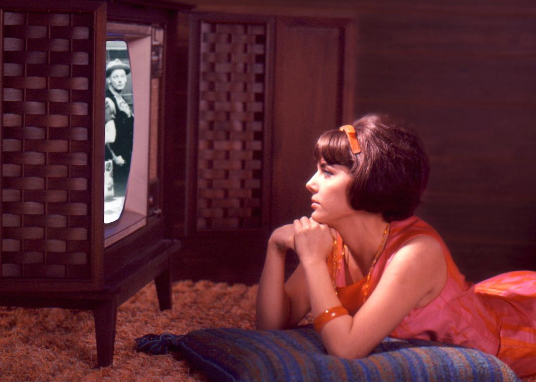 A composite image shows a young person in a pink and orange dress watches an episode of 'The Honeymooners' on a console TV set in the late 1960s or early 1970s.