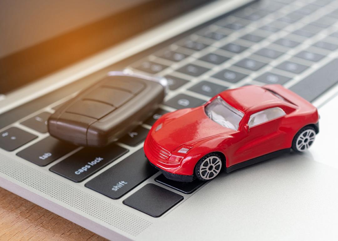 A figure of a red car and car key on top of a laptop.