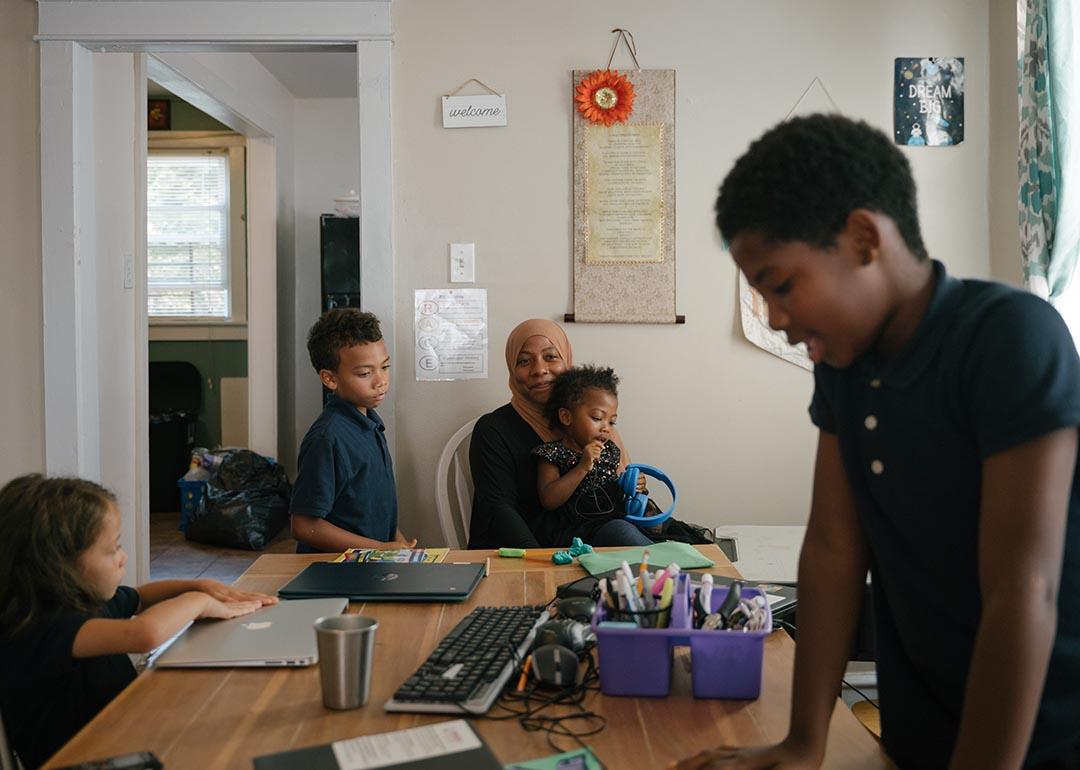 Sameerah Abdullah holds her daughter Maimoonah Abdul Hakeem, 3, while her children Asiyah Jones (left), 6, Dawud Jones, 7, and Musa Moore, 9, do schoolwork in their home in Philadelphia.