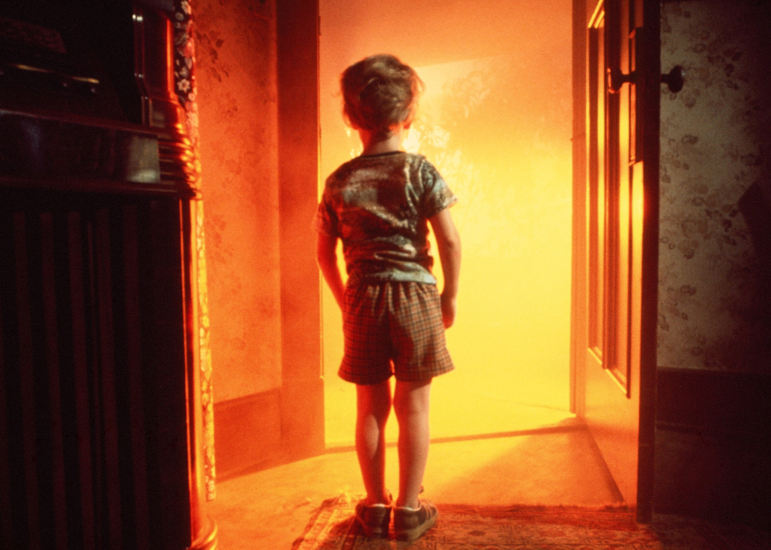 A young Cary Guffey staring at a doorway with a bright orange light shining through it in a scene from the movie 'Close Encounters of the Third Kind' in 1977.