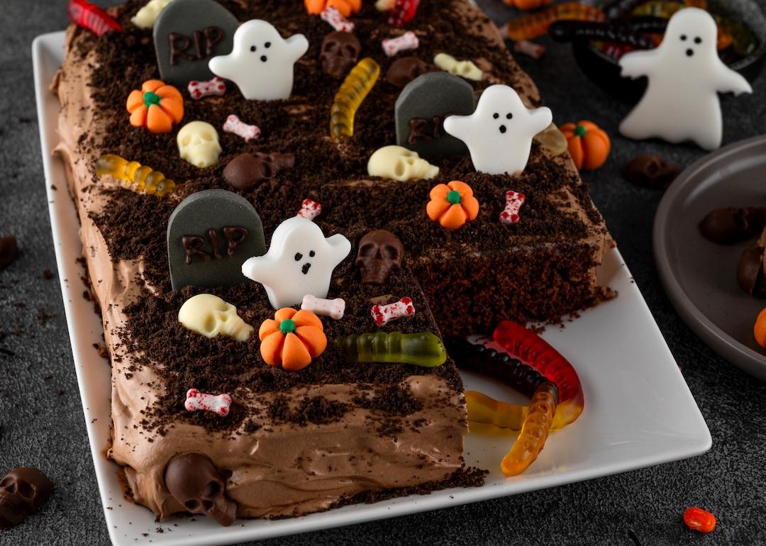 Dirt cake with chocolate cream, decorated with worms, skulls, ghosts, pumpkins, and sugar sprinkles for Halloween.