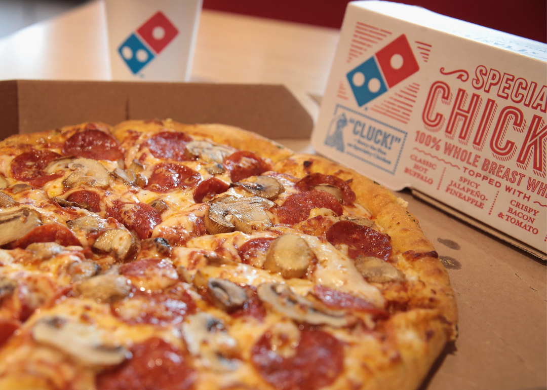 A pepperoni and mushroom pizza from Domino's, with a Domino's box and drink cup in the background