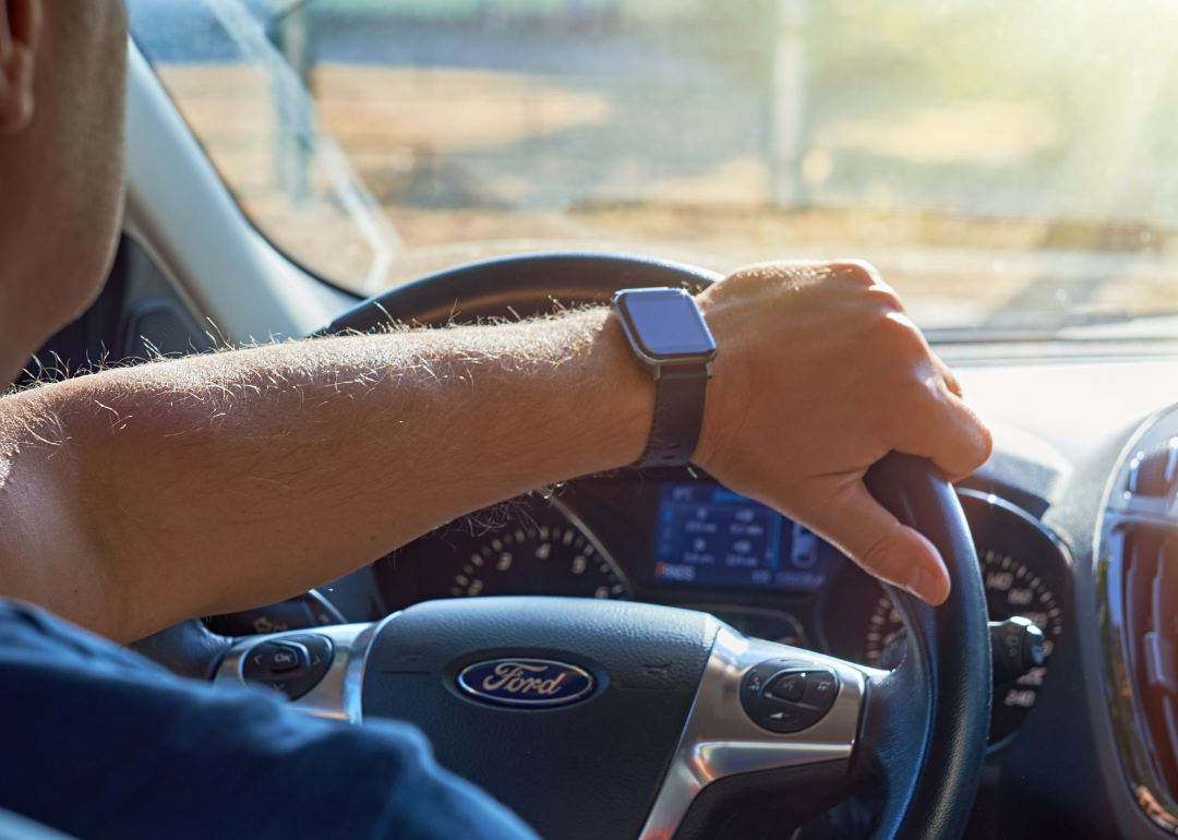 Close-up of a person’s arm gripping the steering wheel of a Ford car.