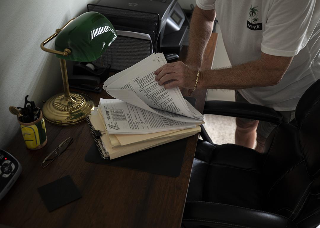 A senior Florida homeowner flips through insurance documents after his home is damaged by a hurricane.