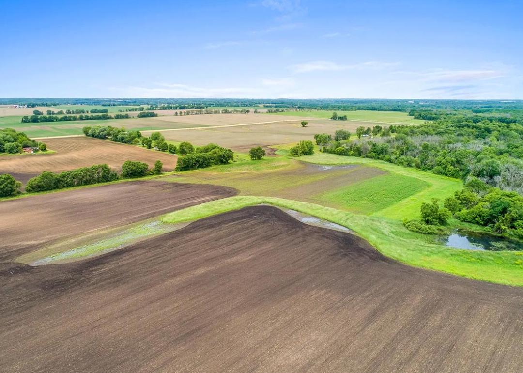 Aerial view of farmlands, soil, with blue sky in background.