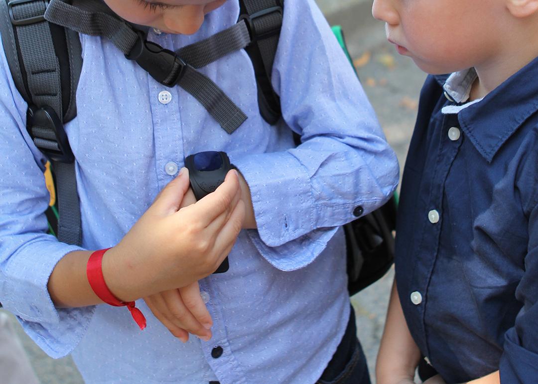 Young boy shows another child a smartwatch with a GPS tracker.