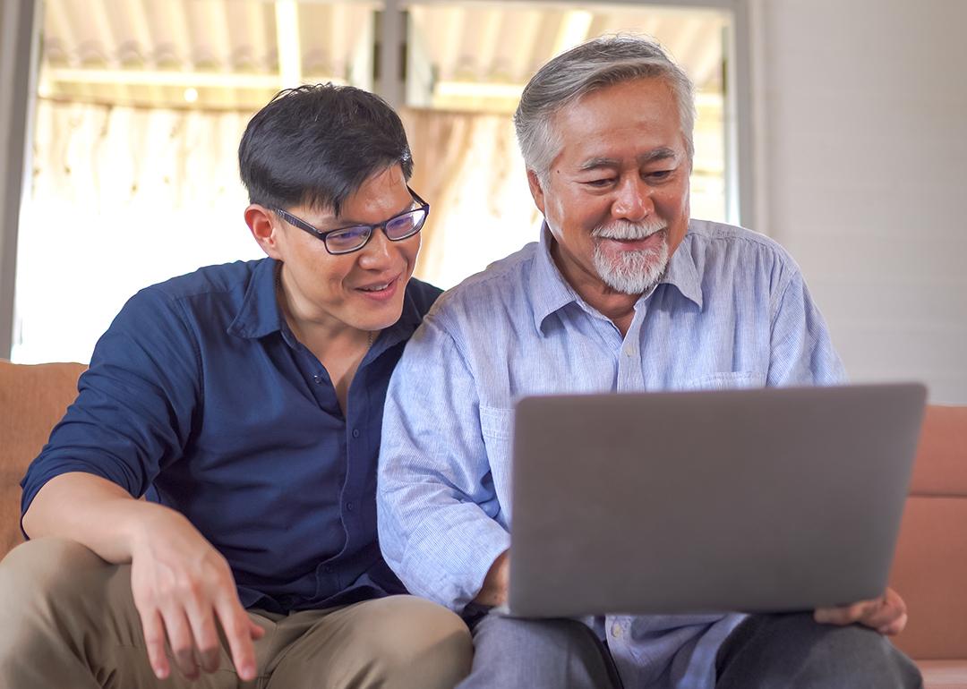 A senior father and his young son looking at information using a laptop at home.