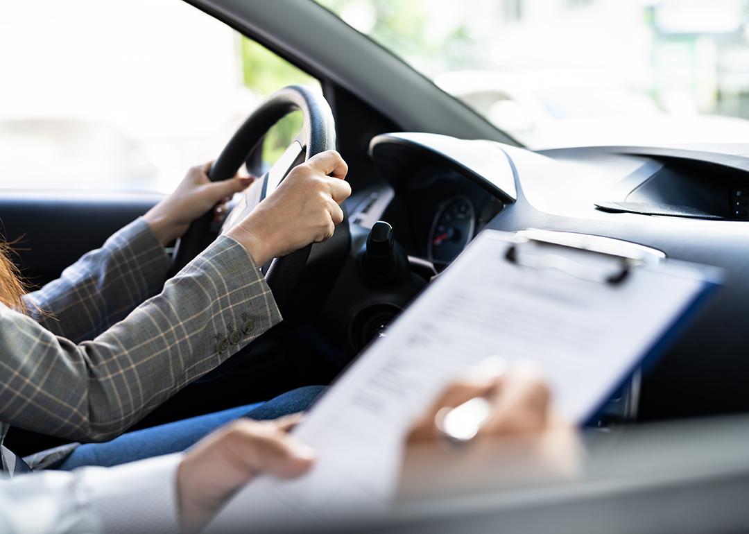 A female driver taking driving lessons with an instructor inside the car.