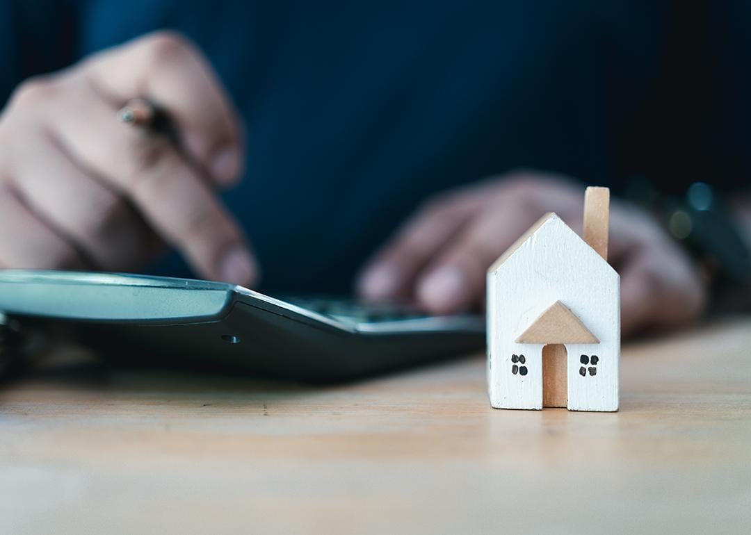 Person calculating interest rates with a house figure on the side.