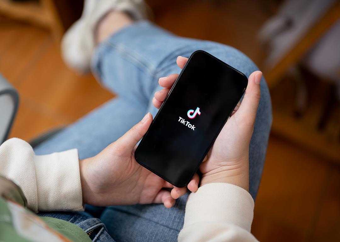 Person holding a phone with the Tiktok app opening.