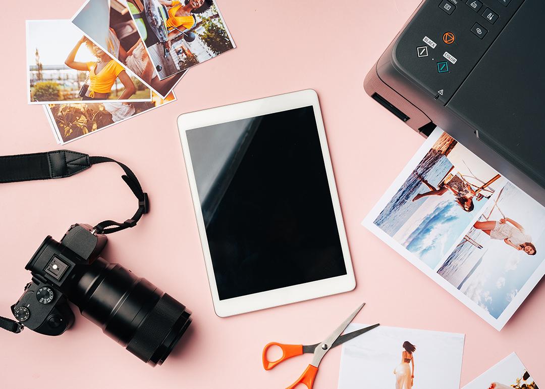 A flatlay of gadgets such as a photo camera, tablet, and printer used to archive digitally.