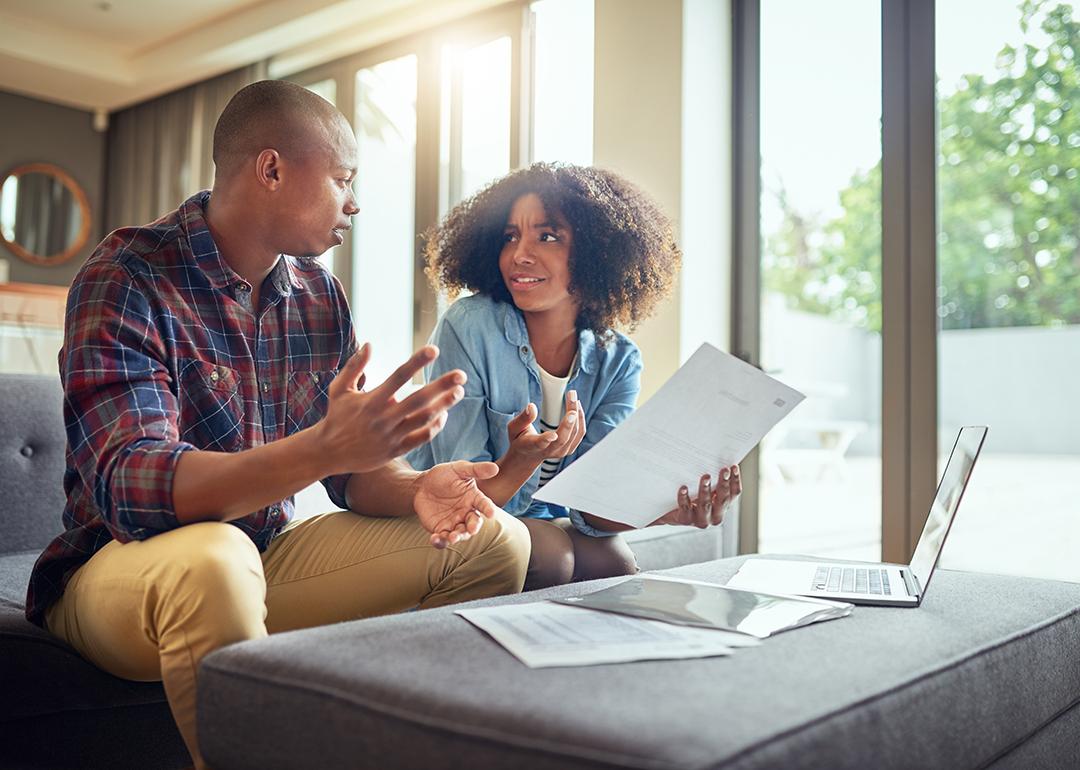 Two people discussing financial paperwork looking confused.