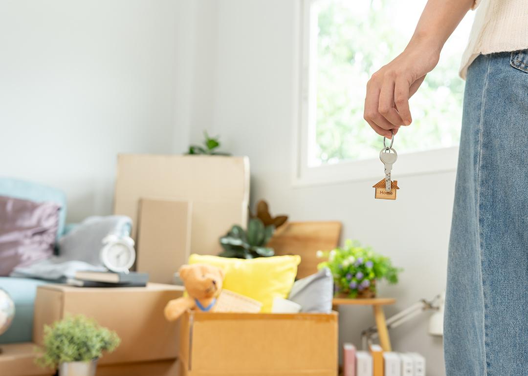 Person holding house keys while seemingly staring at moving boxes and packed items.