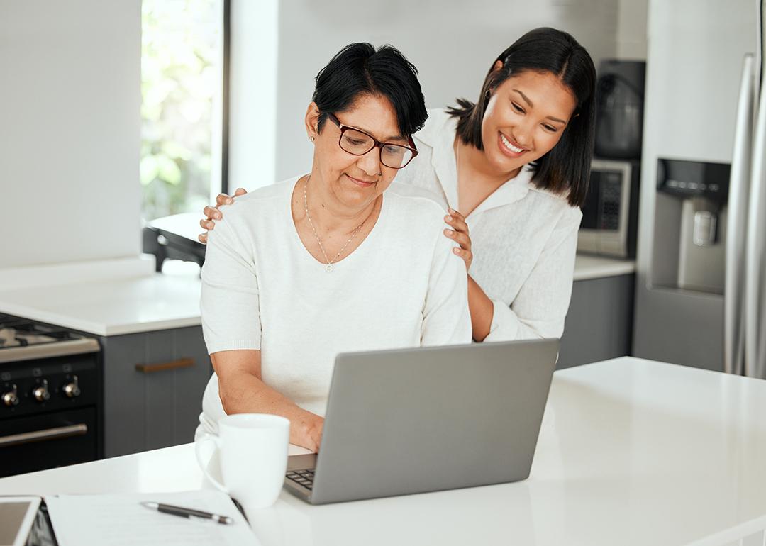 Older mother and her adult daughter looking up finance and retirement information using a laptop.