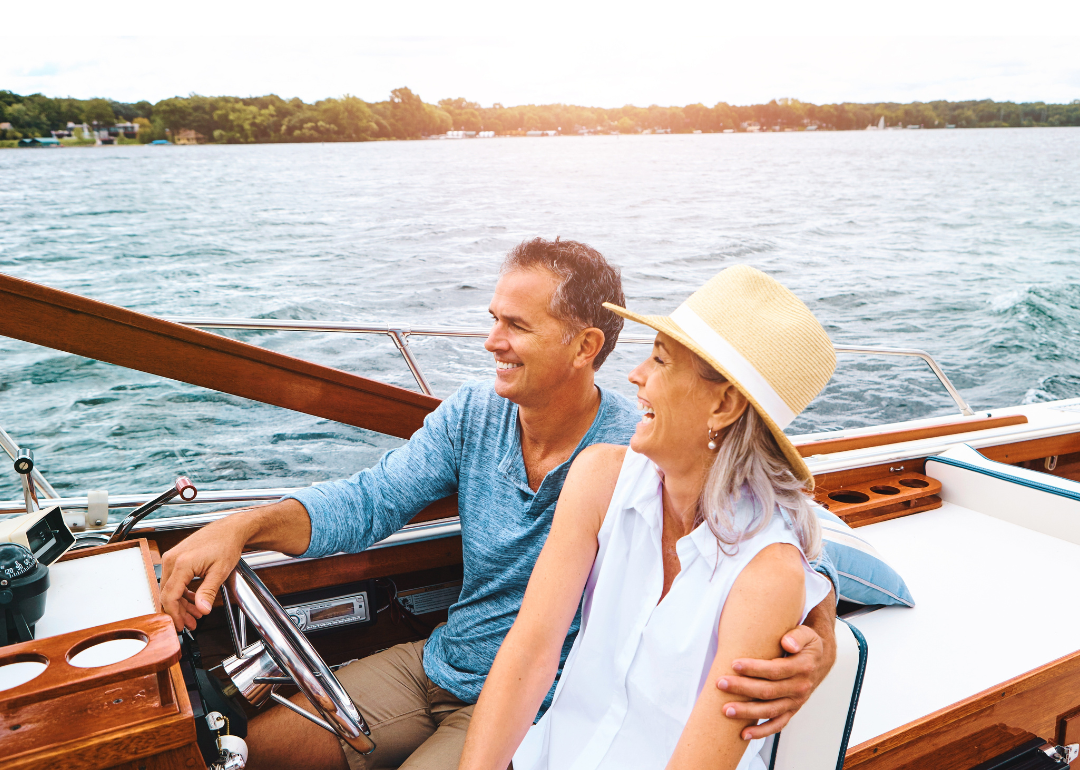 An old retired couple driving a boat on a lake at sunset