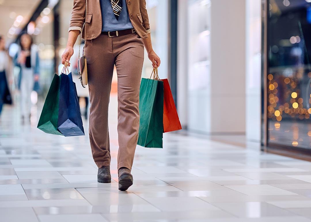 Photo showing close-up of shopping bags as shopper walks through retail mall.