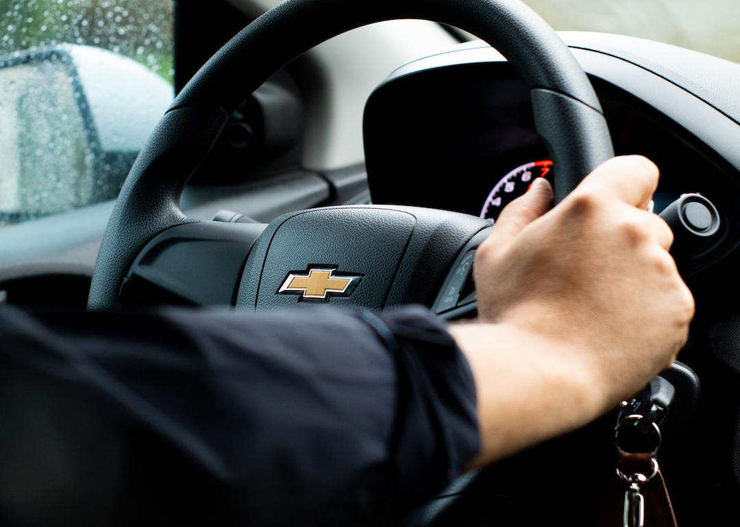 Person's hand on a Chevrolet steering wheel.