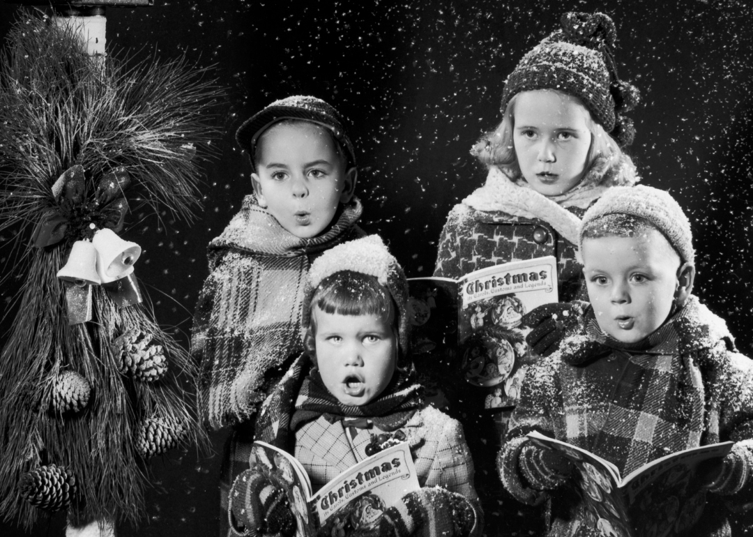 Four children singing carols, from a caroling book entiled 'Christmas, Its' Carols, Customs and Legends,' circa 1955.