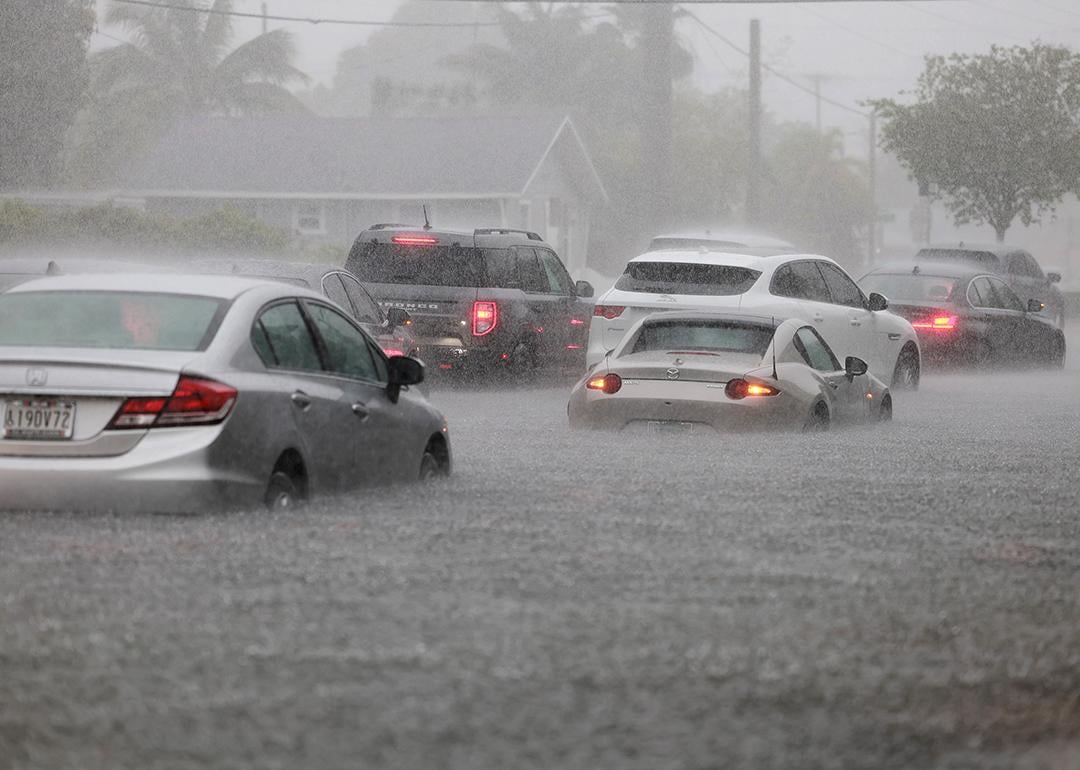 Cars are parked in a flooded street in Dania Beach, FL.