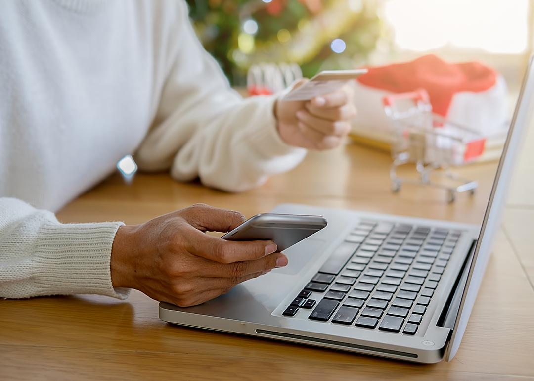 Person shops online during the holiday season using credit card and phone.