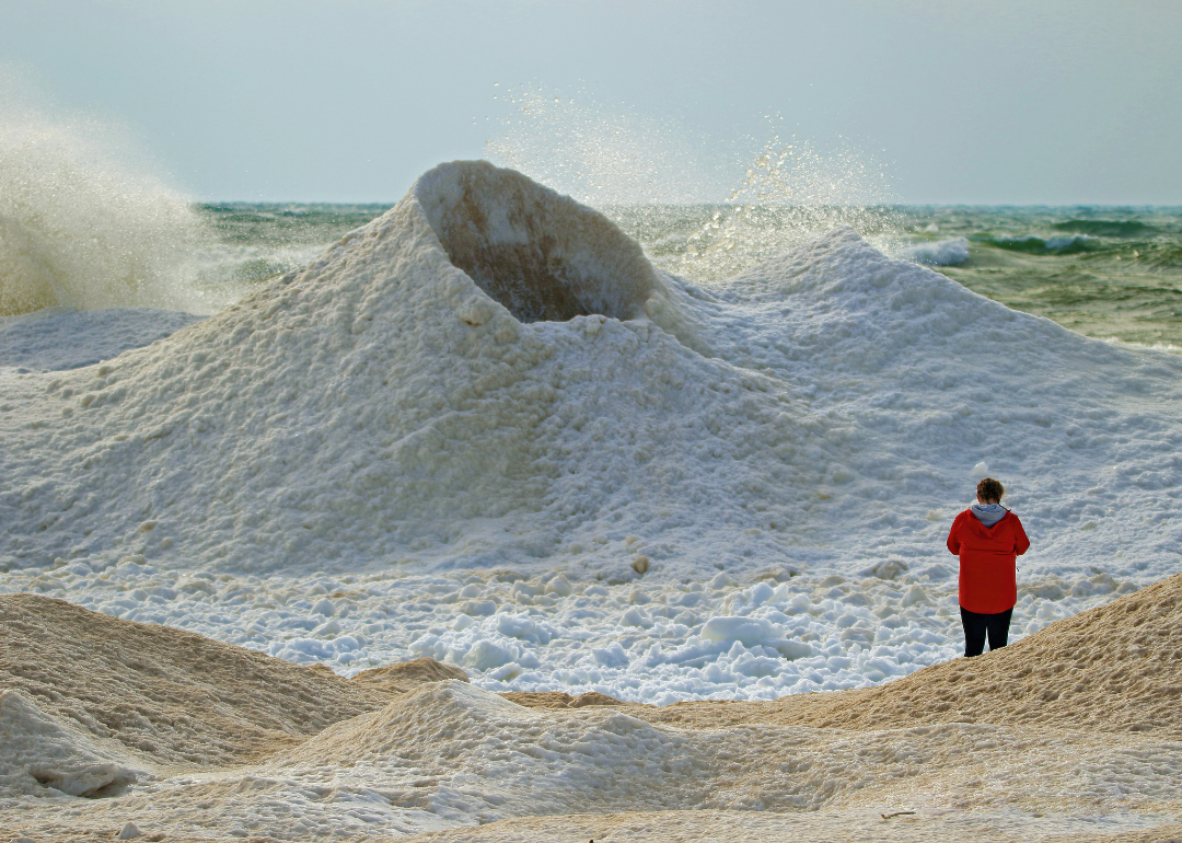 Person standing next to an ice volcano on the shores of Lake Michigan