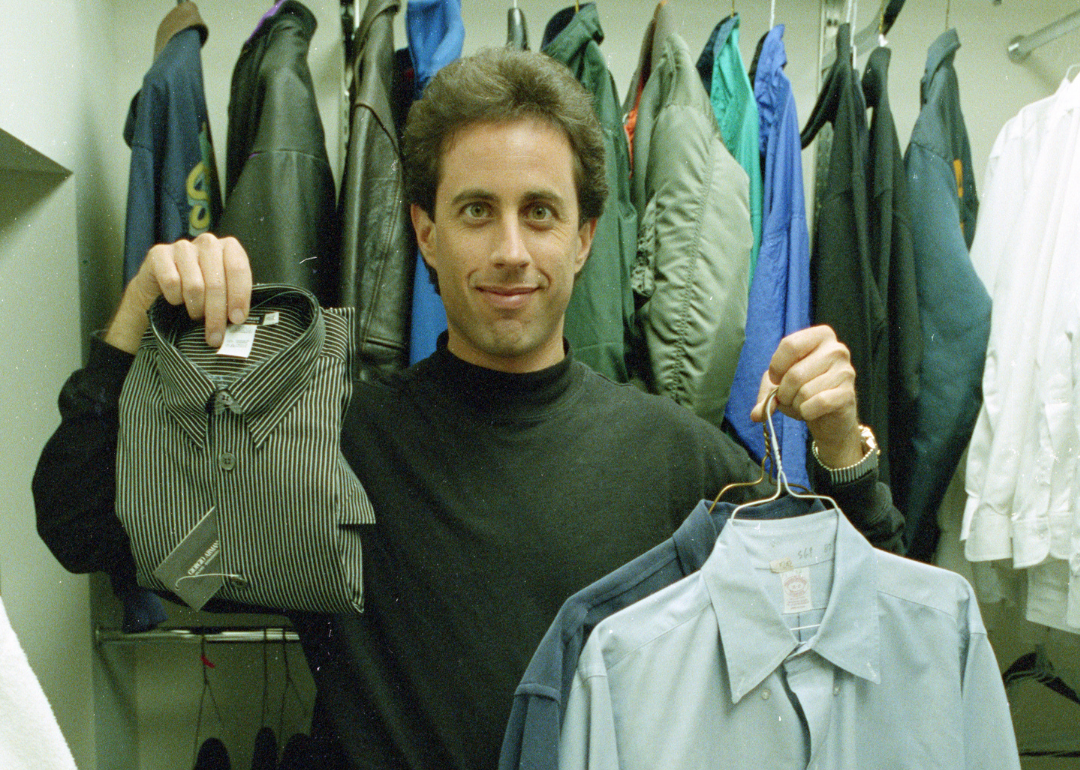 Jerry Seinfeld standing in a closet holding up clothes