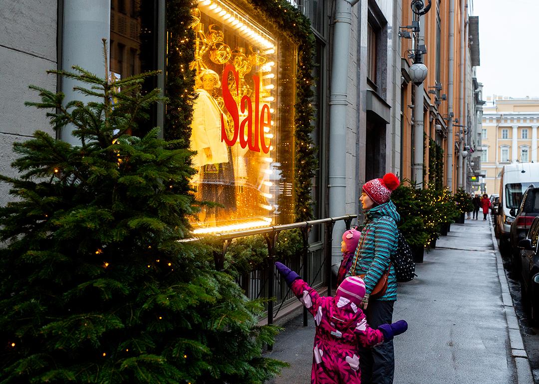 A mother and son looking at a boutique's window with a huge sale sign during Christmas shopping season.